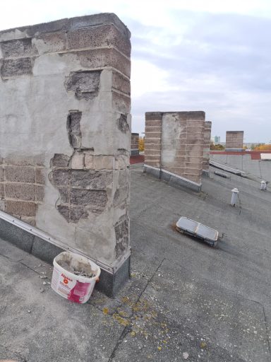 Blick auf eine Dachfläche mit unverputzten Wänden und einem Eimer auf dem Boden.