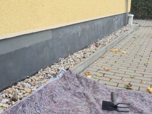 Ein gepflasterter Bereich mit einer grauen Wand und einem Schaufelwerkzeug auf einer Decke.
